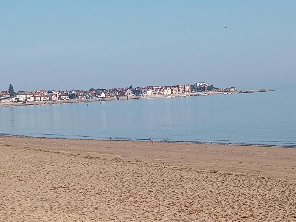 ein Strand mit Gebäuden in der Ferne und dem Ozean in der Unterkunft 3 bed bungalow Penrhyn Bay Llandudno in Llandrillo-yn-Rhôs