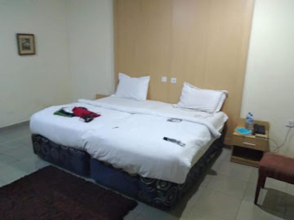 Un dormitorio con una gran cama blanca con una flor roja. en Room in Apartment - Ikogosi Warm Springs - Presidential Lodge, en Ikogosi
