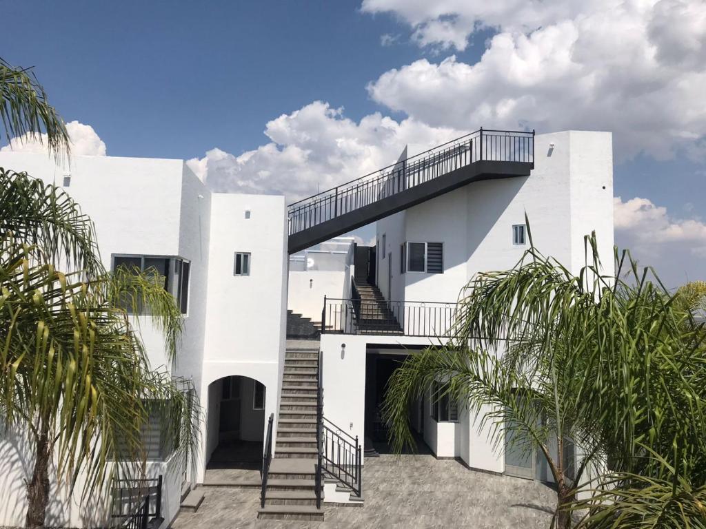 a white house with a staircase and palm trees at Hotel Nuevo Bernal in Bernal
