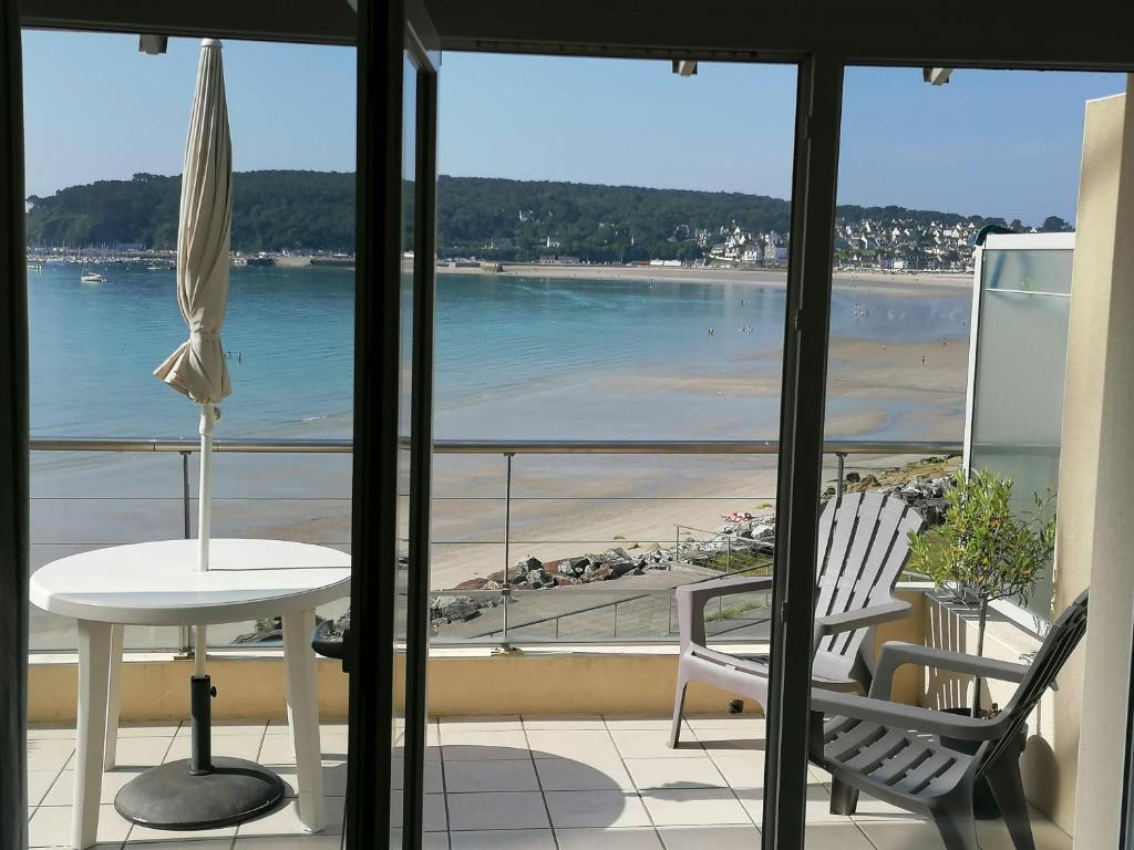 a balcony with a table and chairs and a view of the beach at Cap Morgat chez Jean in Crozon