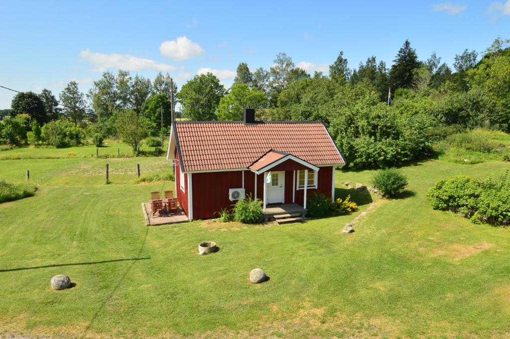 una pequeña casa roja en un campo de hierba en Hustugu Gård, en Örsundsbro