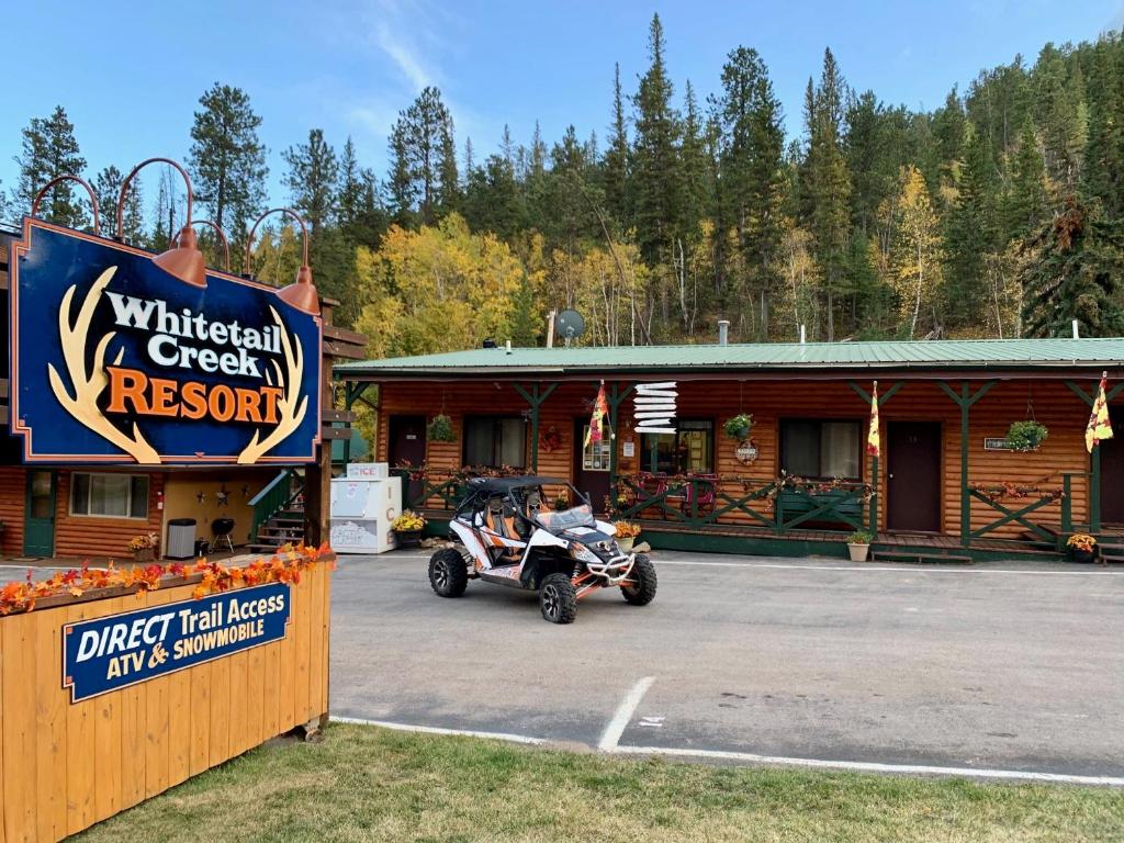 a motorcycle parked in front of a wooden cabin at Whitetail Creek Camping Resort in Lead
