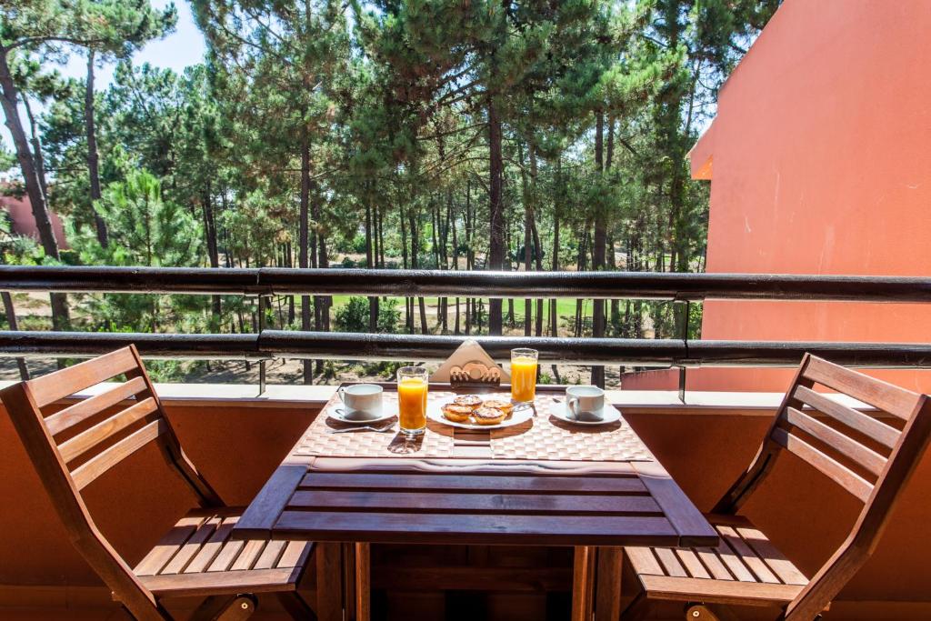 a table with two chairs and two glasses of orange juice at The Golf the Beach and the Unique - Aroeira Apartment in Aroeira