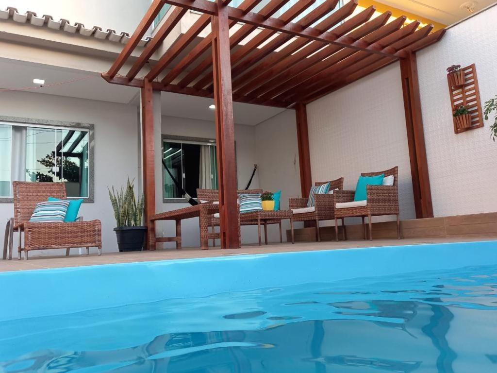 um pátio com uma piscina com cadeiras e uma mesa em Casa com Piscina e Churrasqueira e excelente Localização em Piuma em Piúma