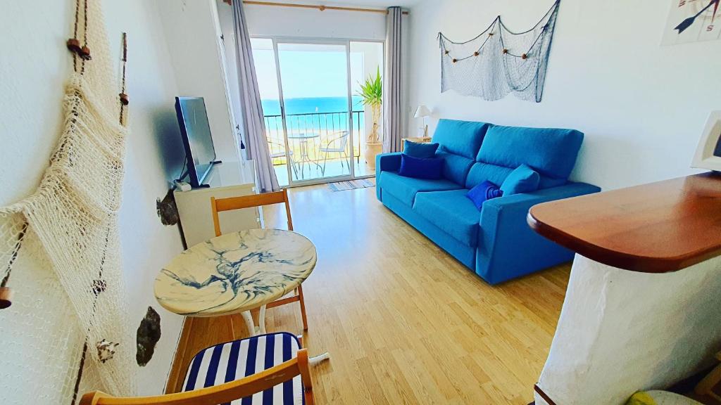 sala de estar con sofá azul y mesa en Cozy beach-front studio with amazing sea view, en Empuriabrava