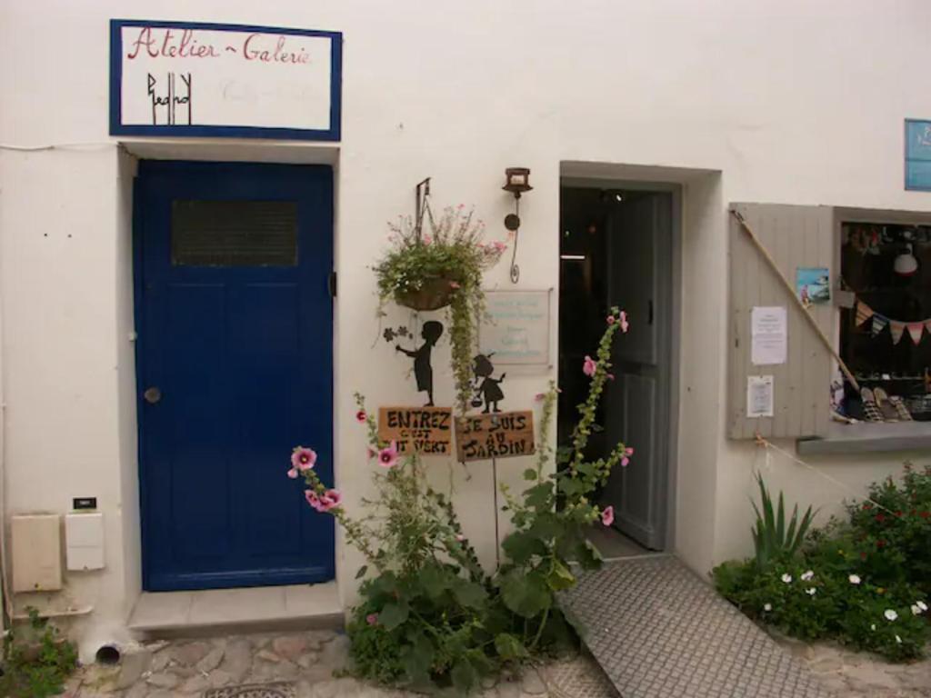 een blauwe deur van een gebouw met bloemen erop bij en plein coeur de Talmont, maison connectée à l'esprit rétais in Talmont