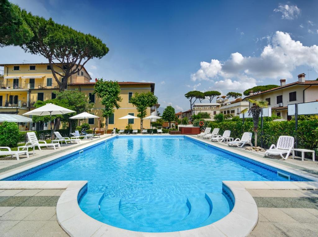 una gran piscina con sillas y sombrillas en Hotel Apuana, en Marina di Pietrasanta