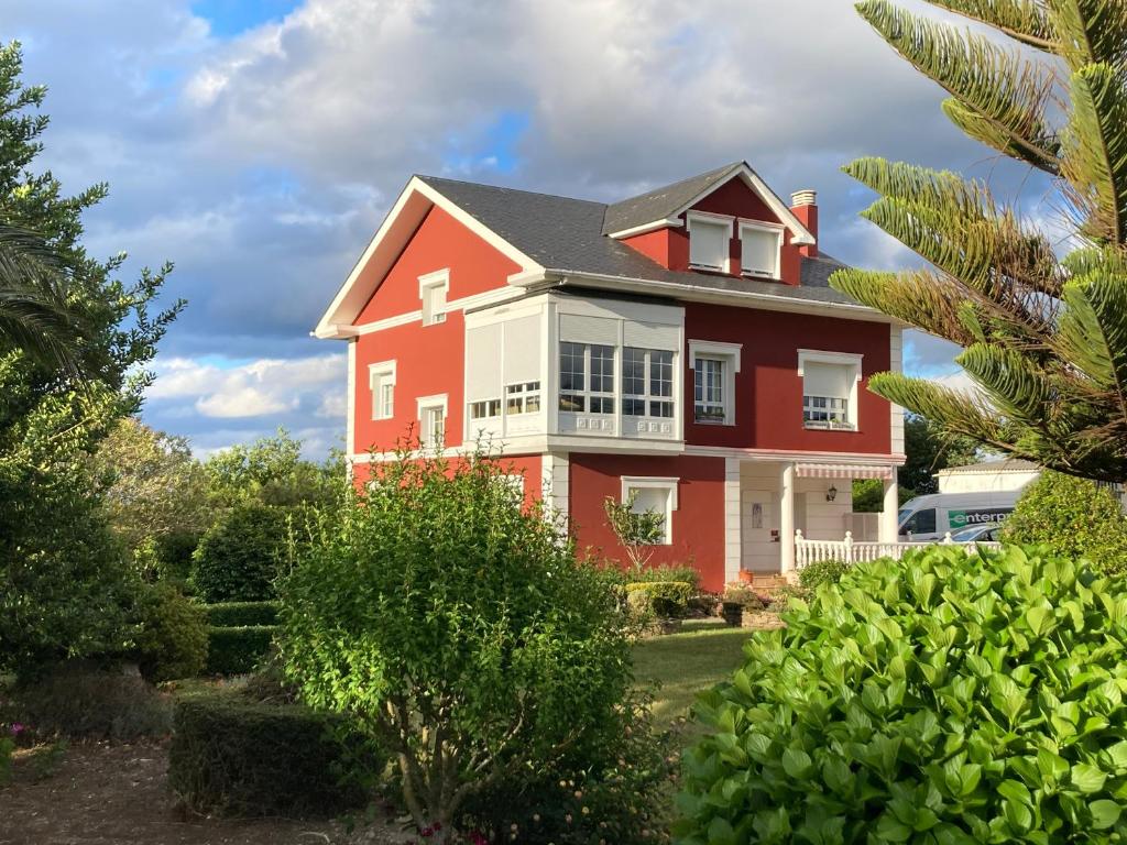 a red and white house with trees and bushes at Casa de Pepa en Ribadeo in Ribadeo