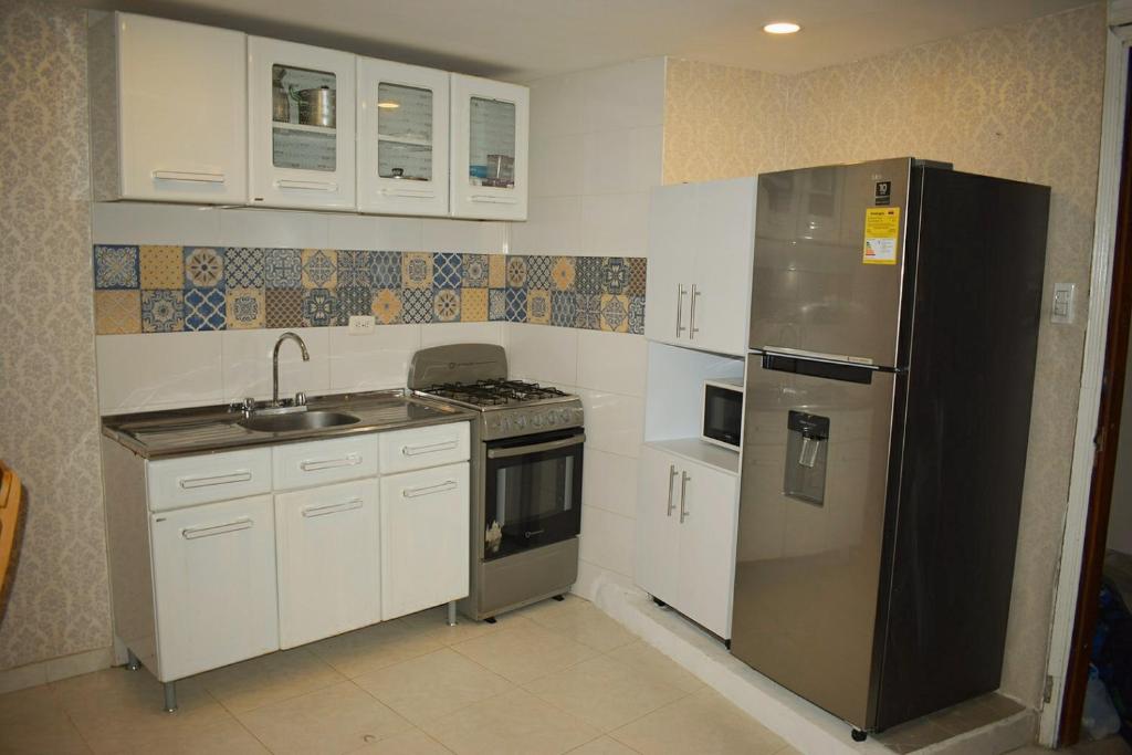 a kitchen with white cabinets and a stainless steel refrigerator at APARTAMENTO EN EL LAGUITO, CARTAGENA in Cartagena de Indias
