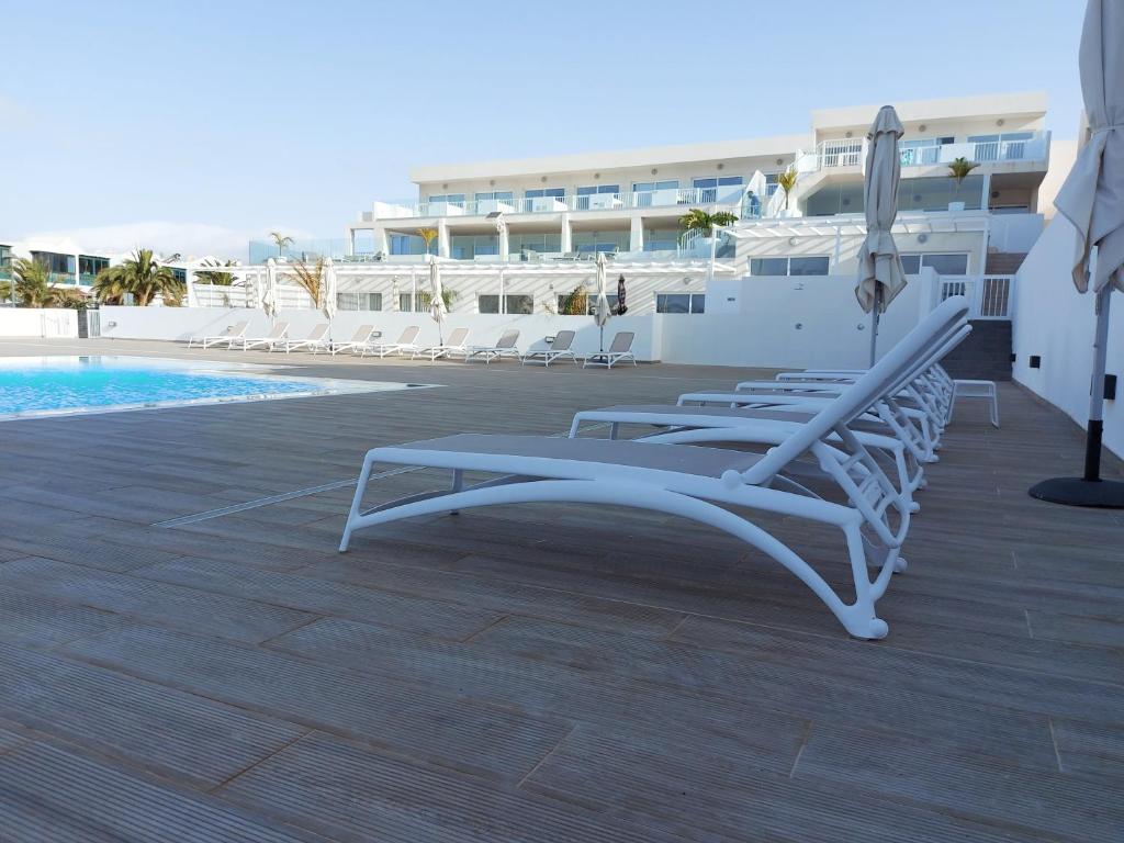 een rij ligstoelen naast een zwembad bij White Suite Deluxe in Costa Teguise