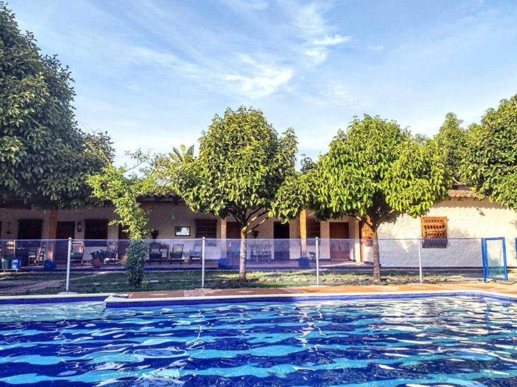 una piscina con alberi sullo sfondo di Hotel Refugio J.G a San Sebastián de Mariquita