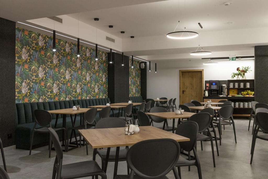 a dining room with tables and chairs and a painting at Hotel Alexander in Krakow