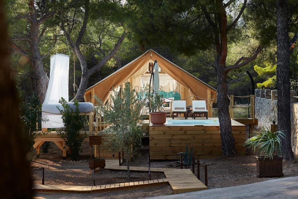 a large wooden house with a porch and a pool at Abeille Maison Glamping Resort Zlatni Rat -Adults Only in Bol