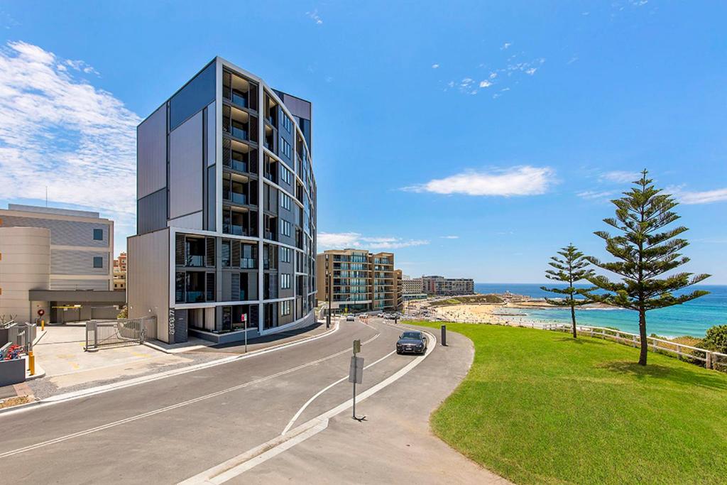 un bâtiment situé sur le côté d'une route à côté de l'océan dans l'établissement Astra Apartments Newcastle Beach, à Newcastle