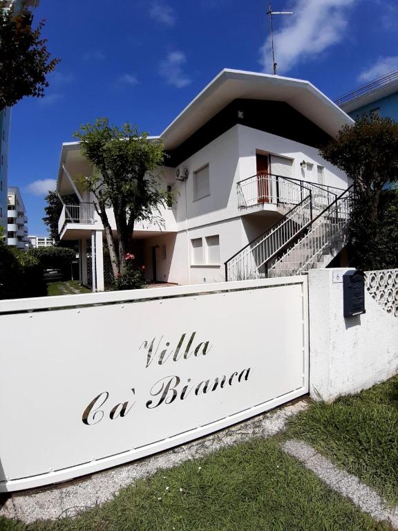 a white house with a sign in front of it at Villa Ca'Bianca in Bibione
