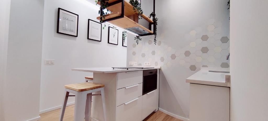 eine weiße Küche mit einer Theke und einem Stuhl in der Unterkunft Estupendo Piso de 2 dormitorios en la Gran Vía. A/A. Wifi. in Salamanca