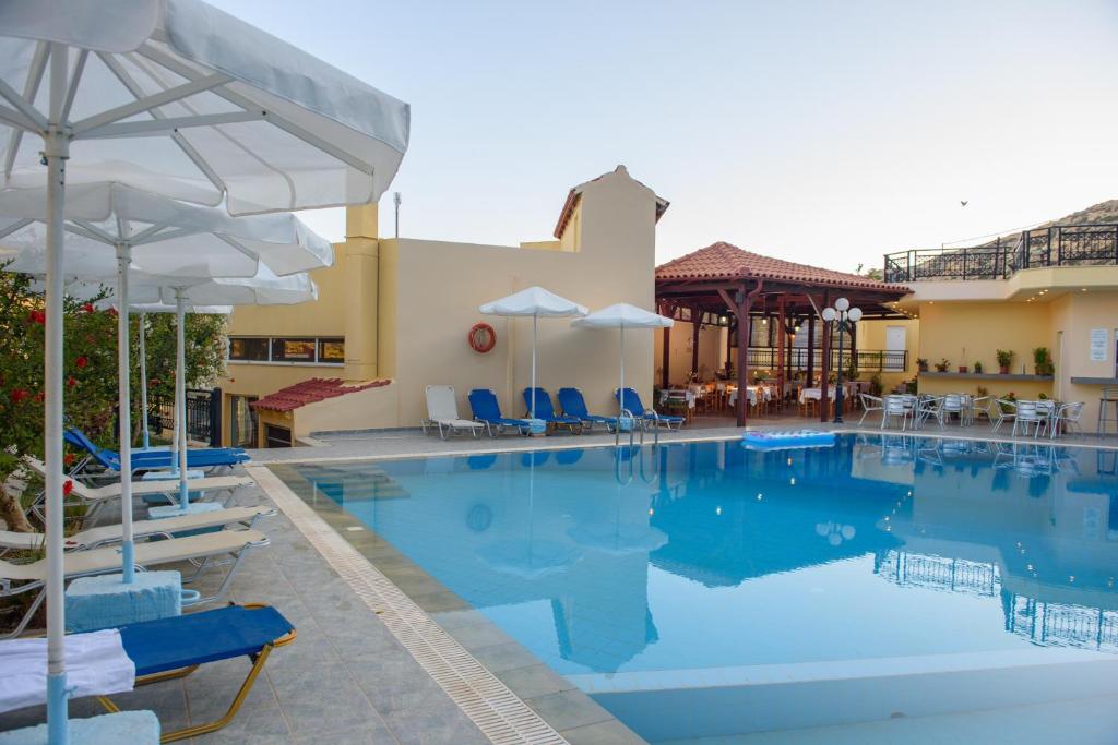 a pool at a hotel with chairs and umbrellas at Melissa Hotel in Matala