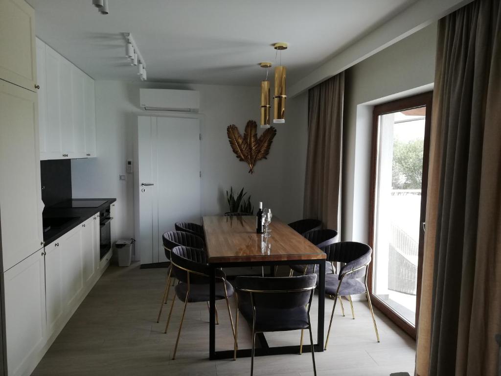a kitchen and dining room with a wooden table and chairs at Apartament Latarnik- BIG in Gąski