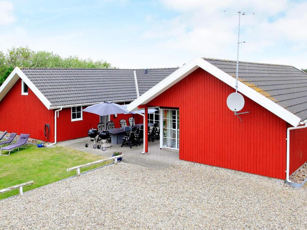 un granero rojo con un patio delante en 14 person holiday home in Vejers Strand, en Vejers Strand