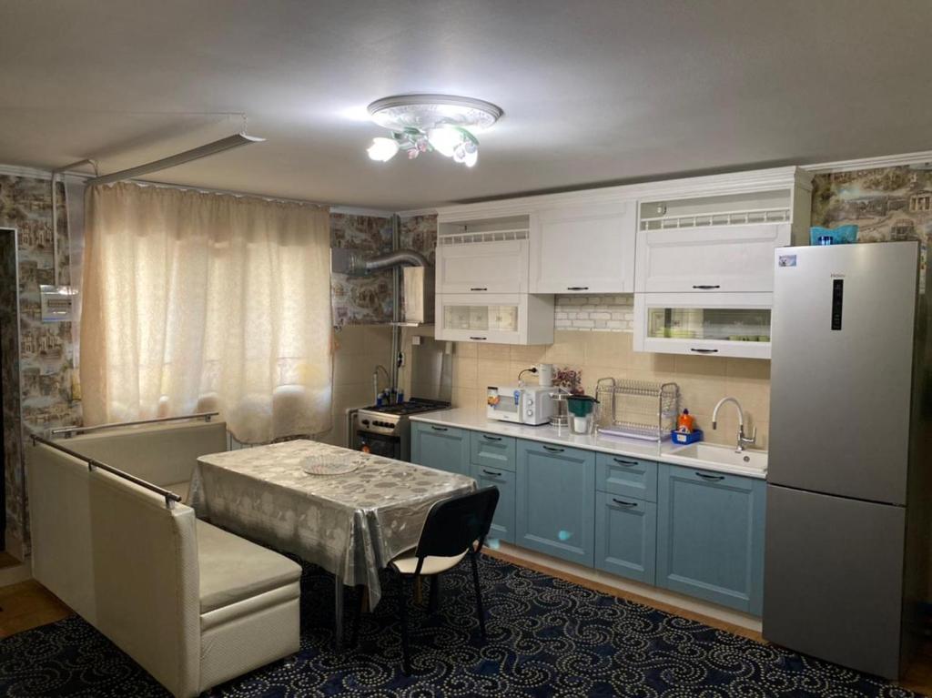 a kitchen with blue cabinets and a table and a refrigerator at Apartment Tsvetochny Tupik in Adler
