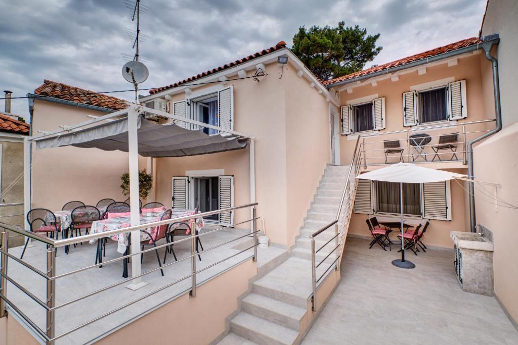 a balcony of a house with a table and chairs at Apartments Ljubica in Veli Lošinj