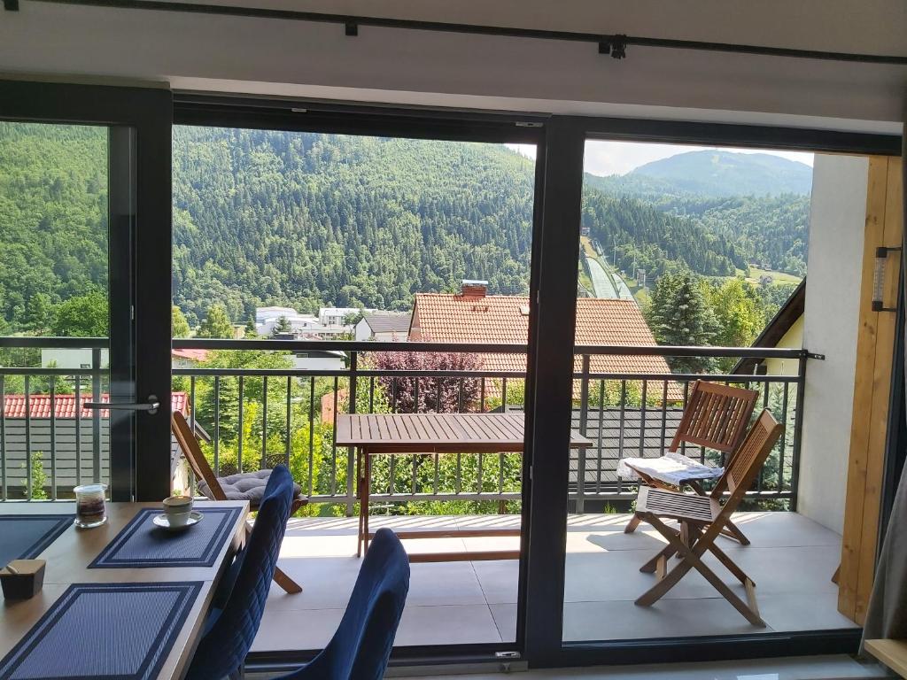 een balkon met een tafel en stoelen en uitzicht bij Apartament Marmurowy w Szczyrku z widokiem na góry z dostępem do sauny i jacuzzi w weekendy, dwa miejsca parkingowe in Szczyrk
