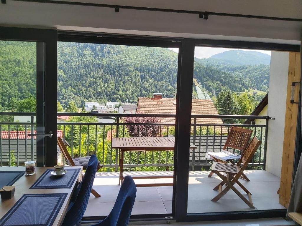 a balcony with a table and chairs and a view at Apartament Marmurowy w Szczyrku z widokiem na góry z dostępem do sauny i jacuzzi w weekendy , dwa miejsca parkingowe in Szczyrk