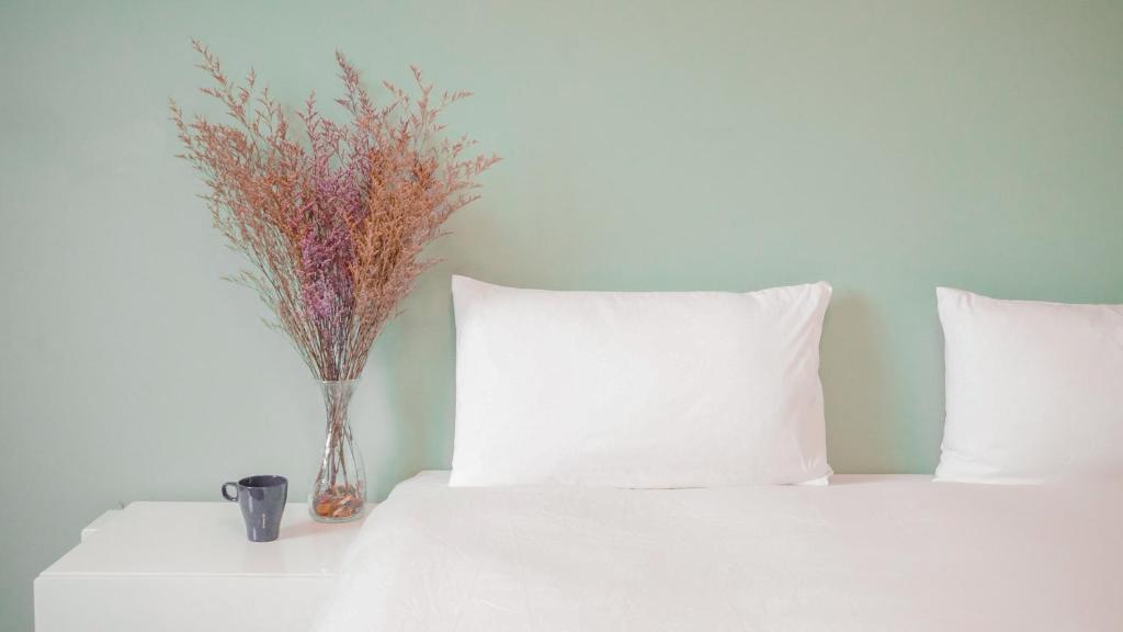 a white bed with a vase of flowers on a table at Ruixiong Hotspring Hotel in Ruisui