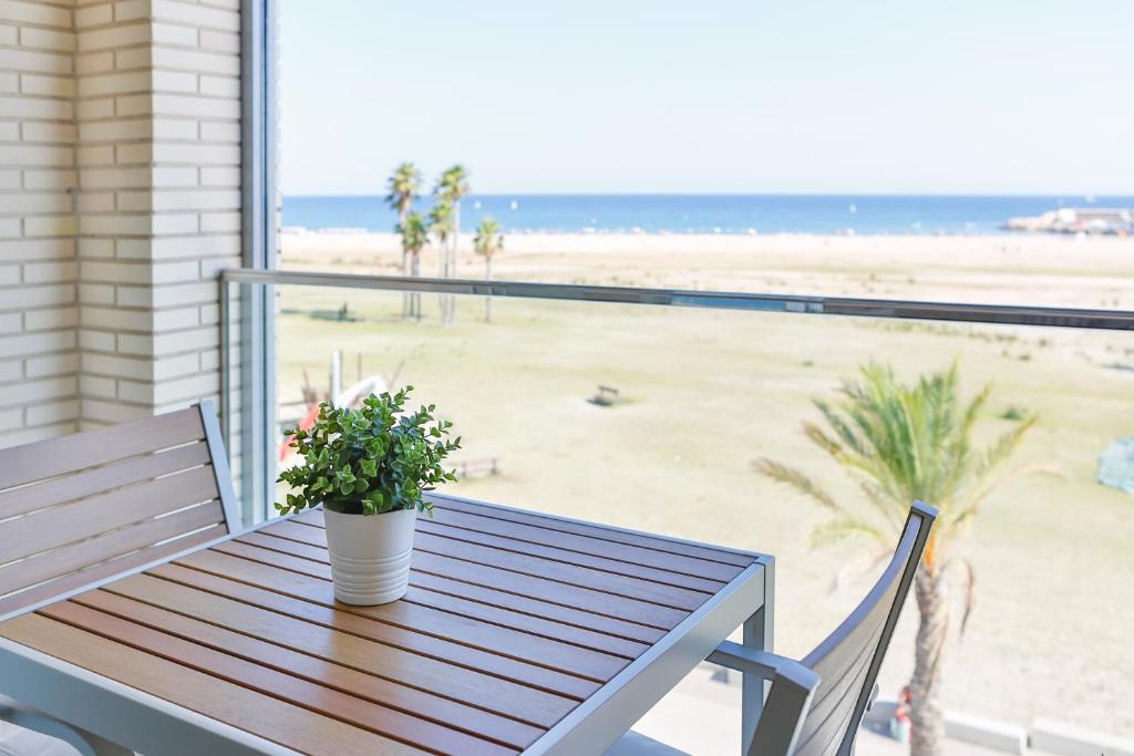 a wooden table with a potted plant on a balcony overlooking the beach at Apartaments Les Palmeres Coma-ruga in Comarruga