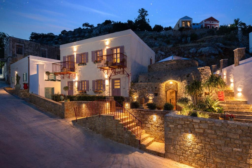 a large white house with a stone wall at Kaminos Boutique Hotel in Symi