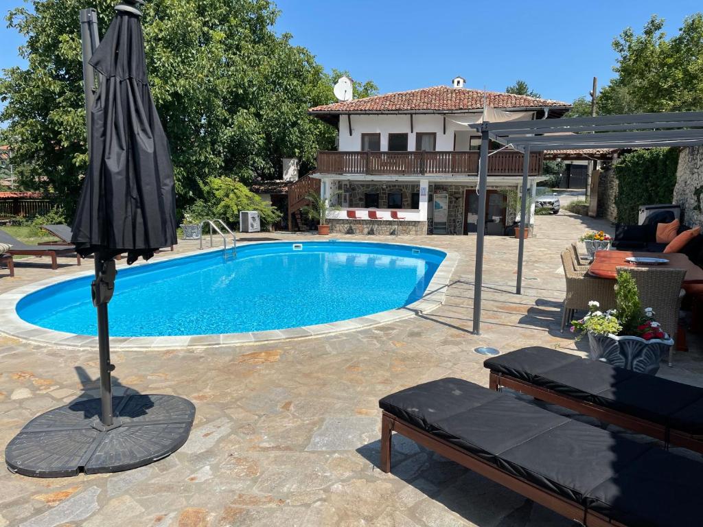 a swimming pool with an umbrella next to a house at Angliiska Vila in Arbanasi