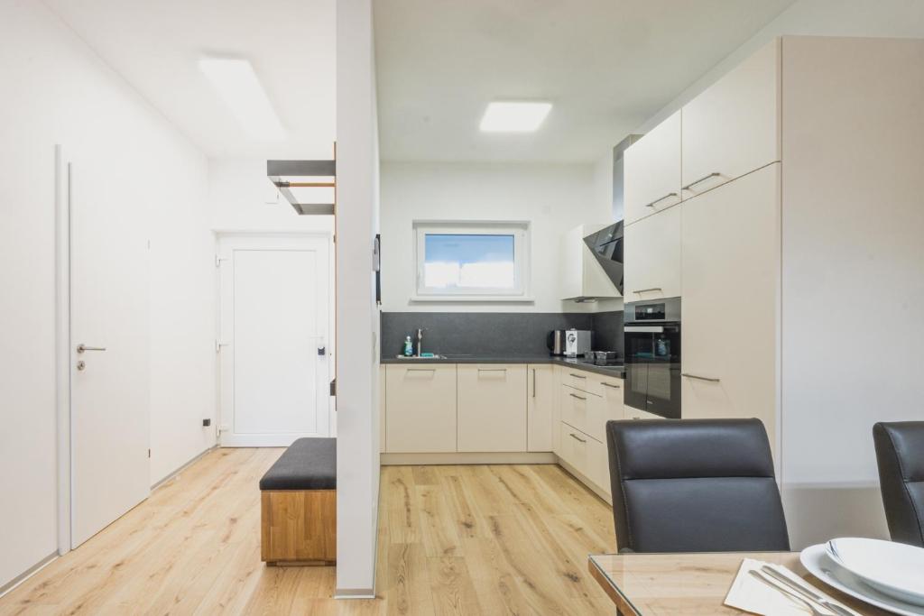 eine Küche mit weißen Schränken sowie einem Tisch und Stühlen in der Unterkunft Deluxe Apartment Graz in Graz
