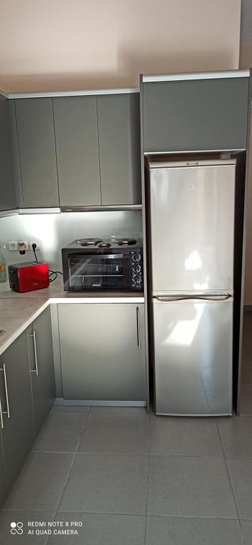 a kitchen with a white refrigerator and a microwave at studio room in Koropi