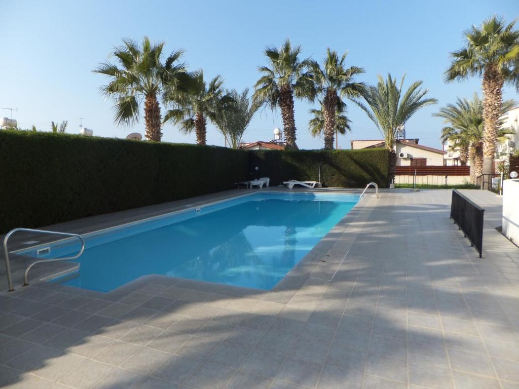 a swimming pool in a yard with palm trees at Cyking Apartment 103 postcode 8046 in Paphos