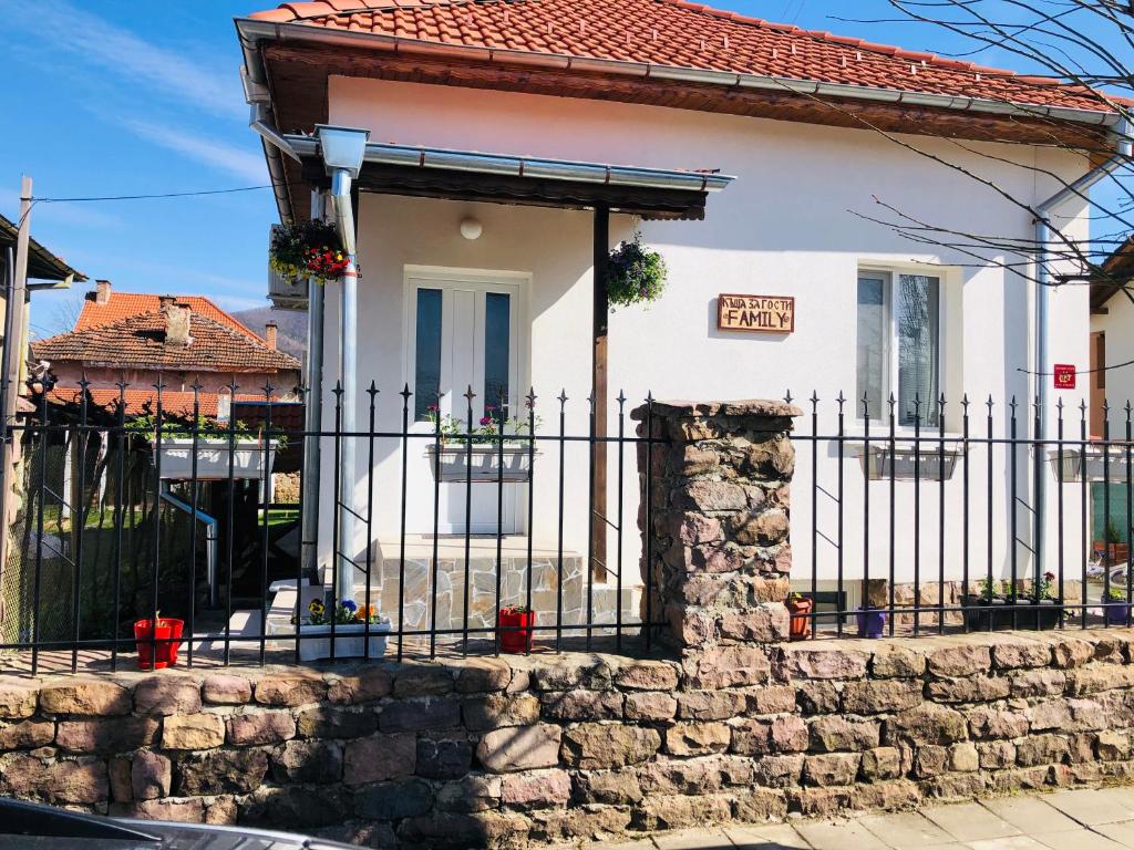 een wit huis met een zwart hek bij Къща за гости “Family” in Varshets
