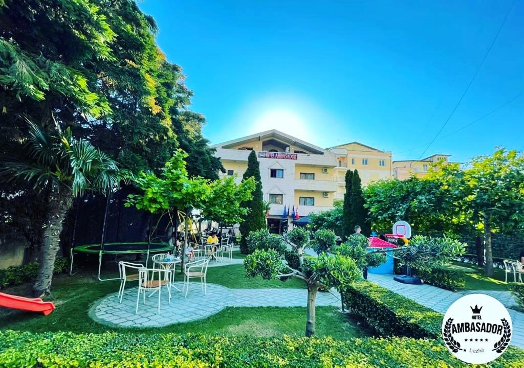 un jardin avec des tables et des chaises en face d'un bâtiment dans l'établissement Hotel Ambasador, à Lezhë