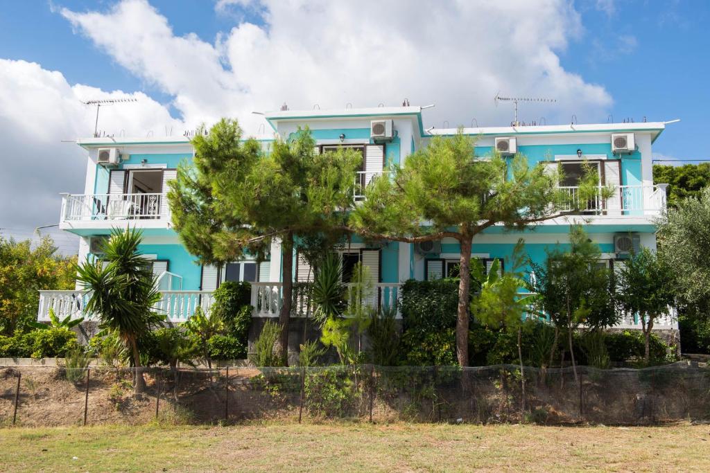 a blue house with trees in front of it at Cleopatra Apartments in Laganas