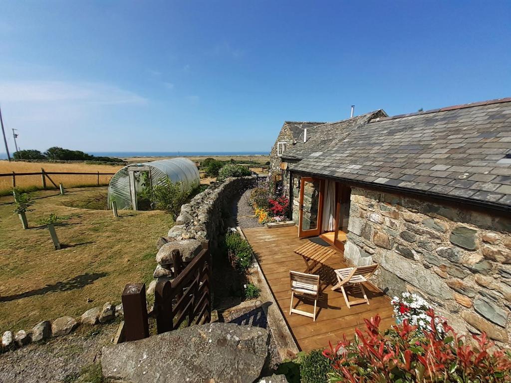 a stone house with a wooden deck and a yard at Bryn Teg Barn in Dyffryn