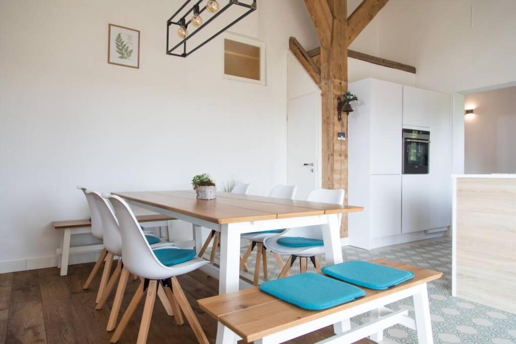 a dining room with a wooden table and white chairs at Moderne Unterkunft Landzeit Esens nahe der Nordsee - ökologisch saniertes Ferienhaus in Esens