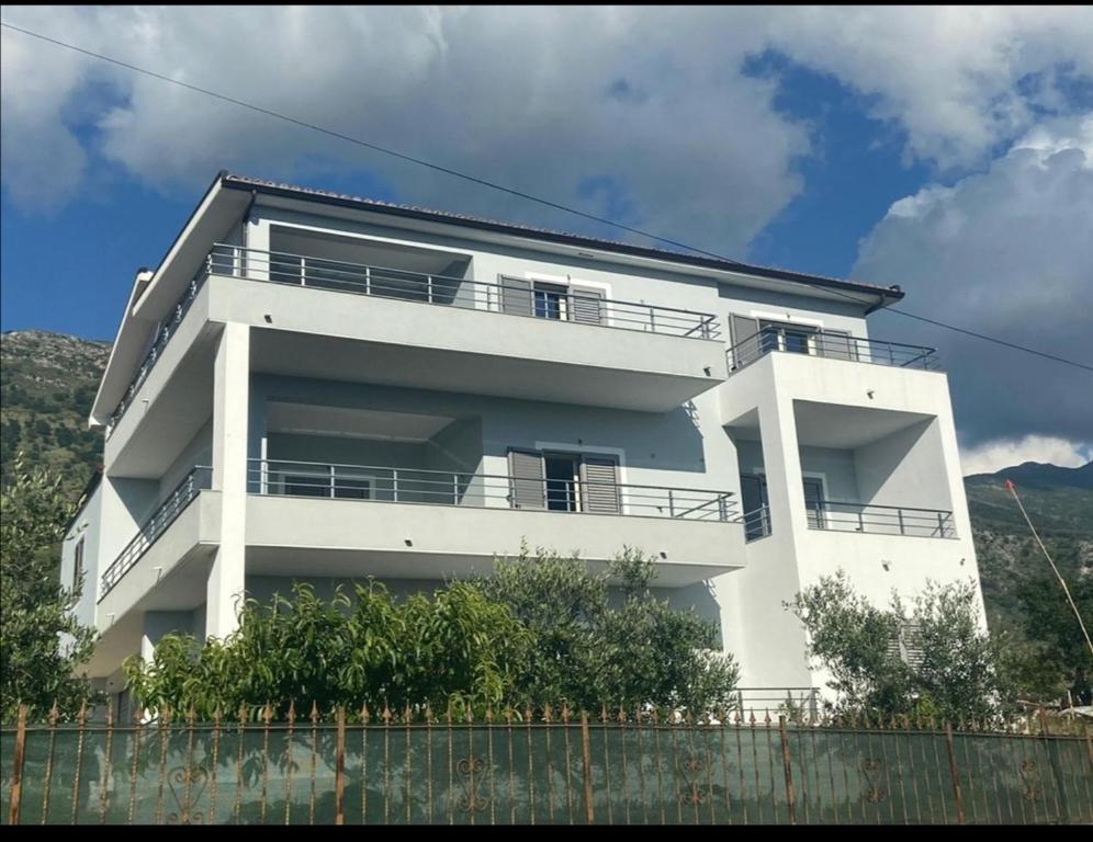 ein weißes Haus mit einem Zaun davor in der Unterkunft Vila Pulo in Tragjas