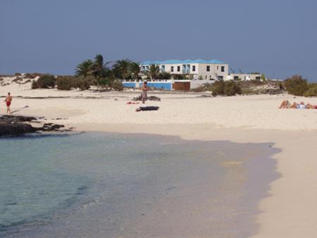 a beach with people on the sand and water at Maravilla Bungalows in Cotillo