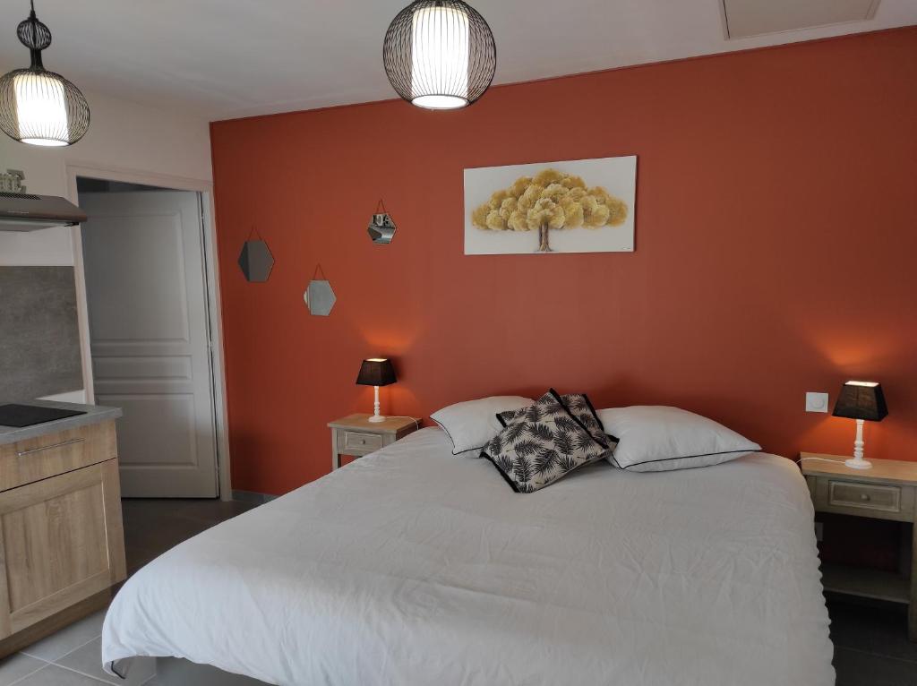 Studio Les chambres de la source - Tadorne في Sancourt: غرفة نوم بسرير ابيض بجدار برتقالي
