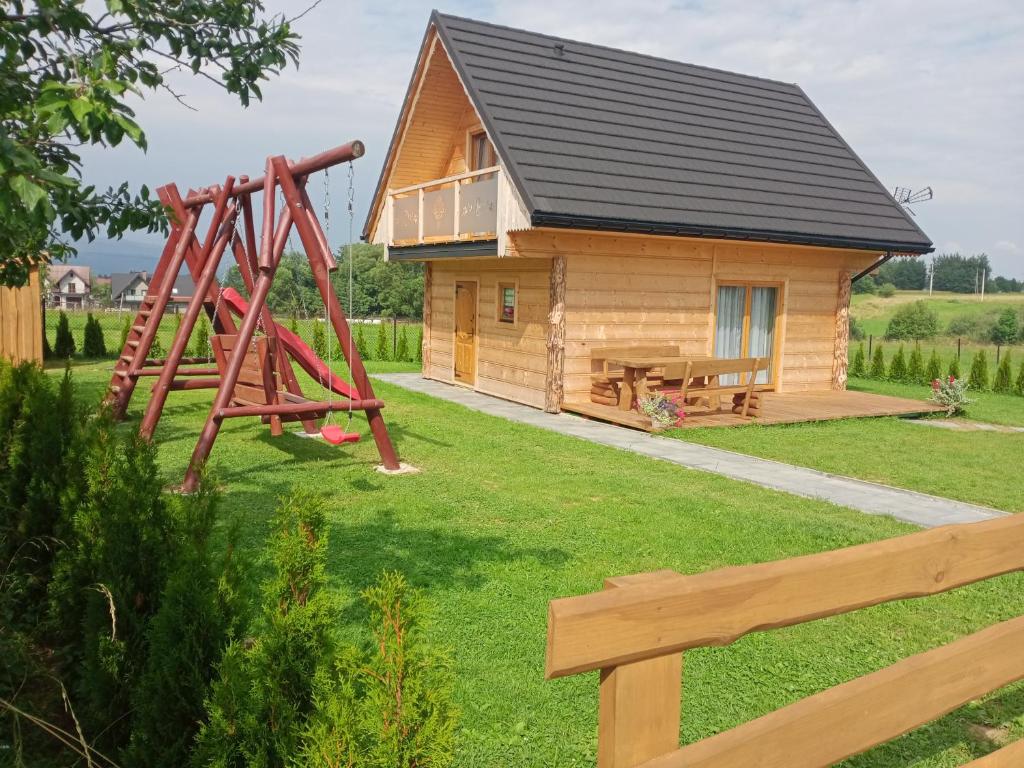 une cabane en rondins avec une aire de jeux et un banc dans l'établissement Domek na farmie, à Szaflary