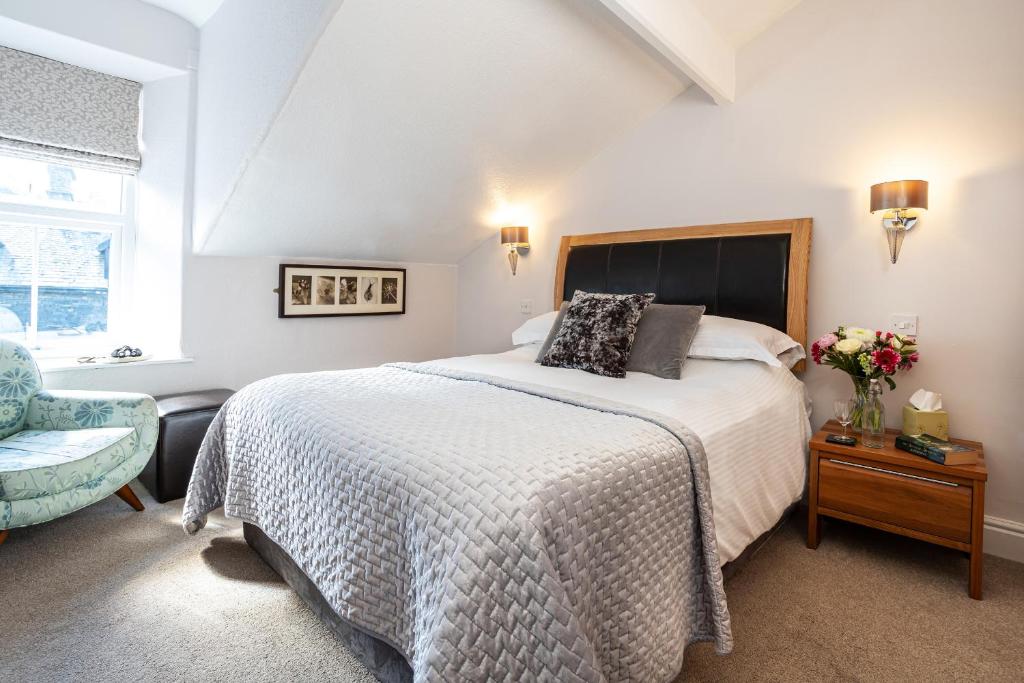 a white bedroom with a bed and a chair at Norwood House in Ambleside