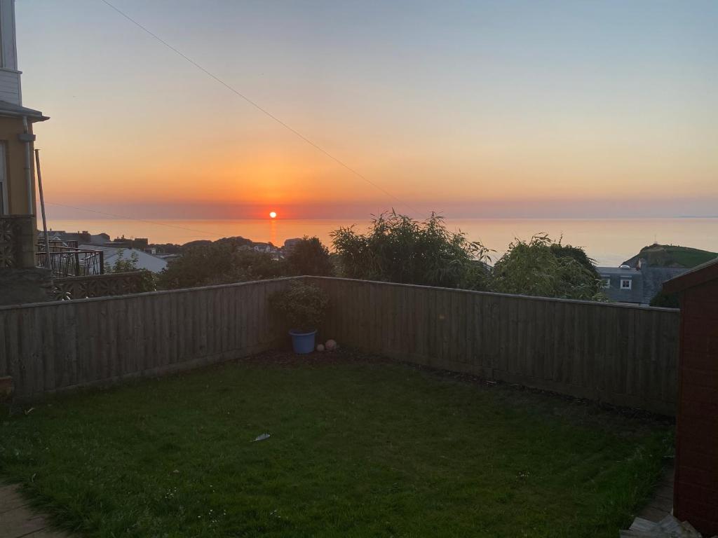ein Sonnenuntergang über einem Hinterhof mit einem Zaun in der Unterkunft Horizon Vista in Ilfracombe