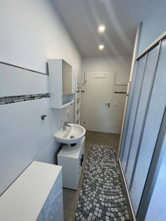 a white bathroom with a sink and a shower at Richter Apartments Finsterwalde 2 in Finsterwalde