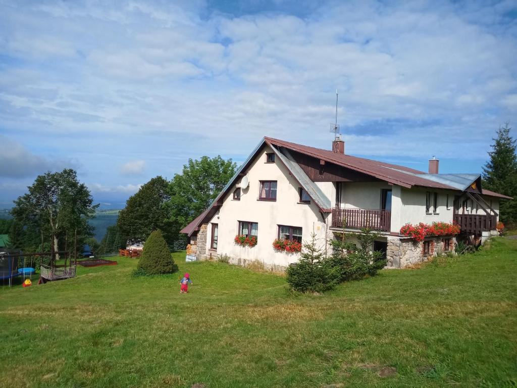 una casa blanca en una colina con un niño delante de ella en Penzion Pochop, en Benecko