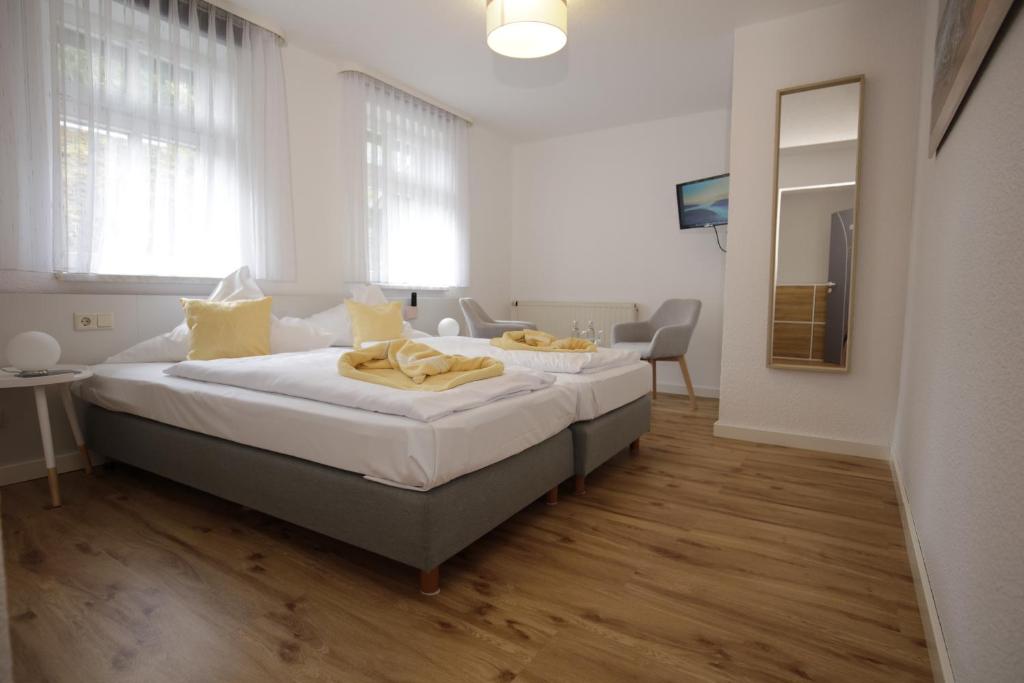 1 dormitorio con 1 cama grande con sábanas blancas y almohadas amarillas en Hotel Beck en Lauscha - Ernsthal am Rennsteig