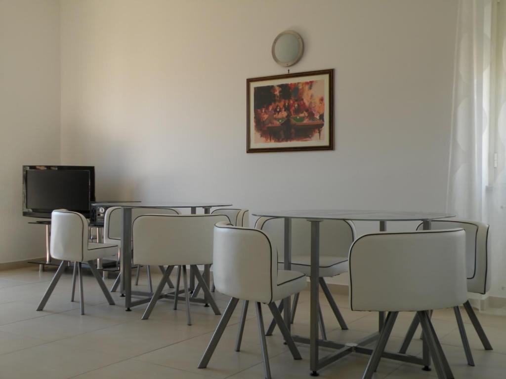 a dining room with white chairs and a table and a mirror at Antares Bed and Breakfast in Syracuse