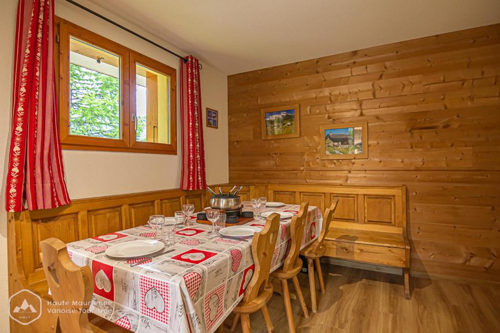 uma sala de jantar com uma mesa e paredes de madeira em Chalets D'Arrondaz em Valfréjus